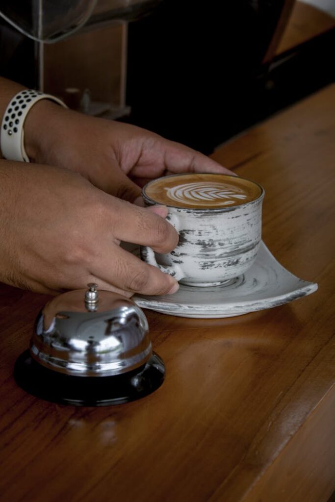 A person holding a coffee cup and a bell